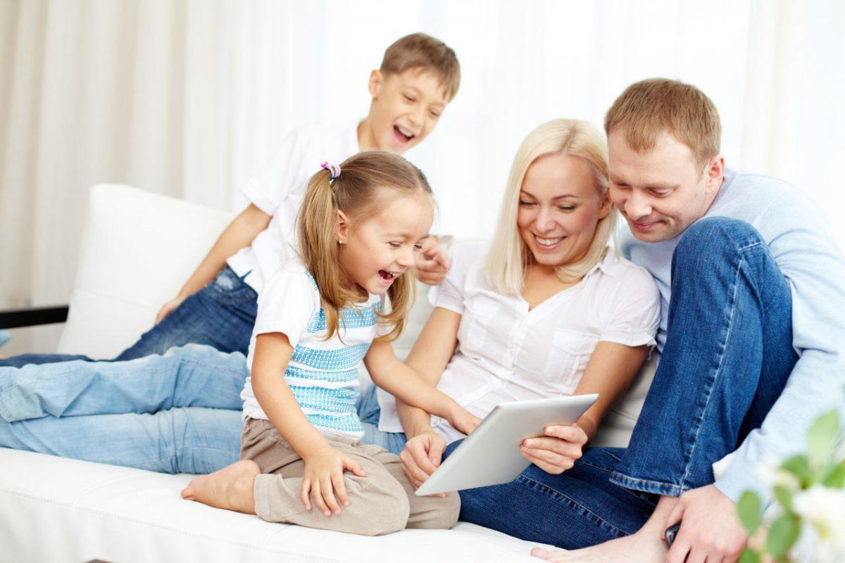 Parents with two children laughing at tablet screen